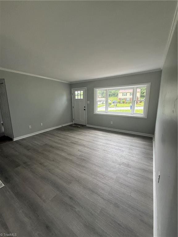 unfurnished living room with crown molding, baseboards, and dark wood finished floors