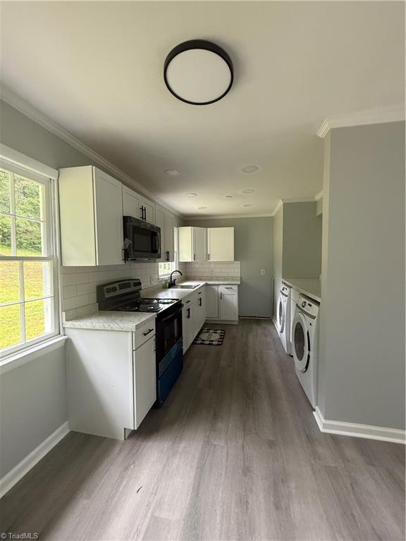 kitchen featuring crown molding, black microwave, range with electric stovetop, dark wood-type flooring, and light countertops