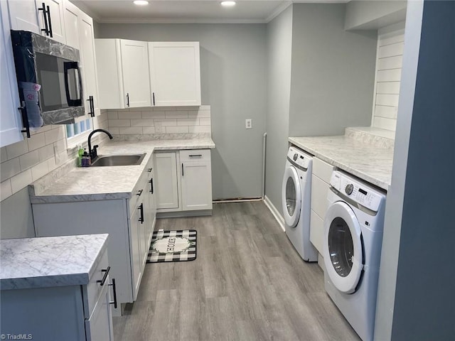 washroom with washing machine and clothes dryer, a sink, recessed lighting, light wood-type flooring, and ornamental molding