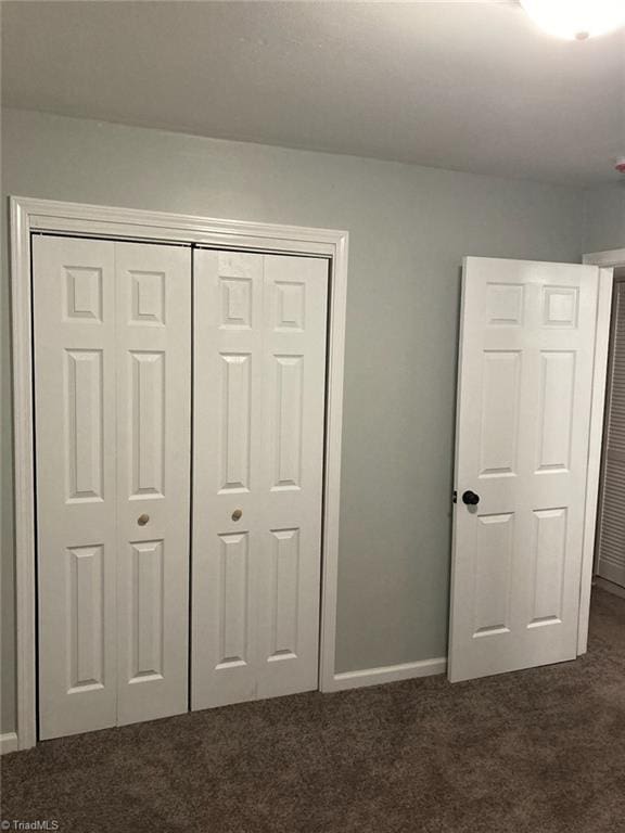 unfurnished bedroom featuring carpet floors, baseboards, and a closet