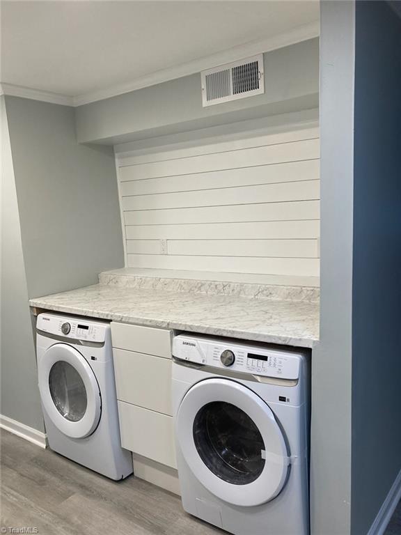 clothes washing area featuring crown molding, laundry area, light wood finished floors, and visible vents