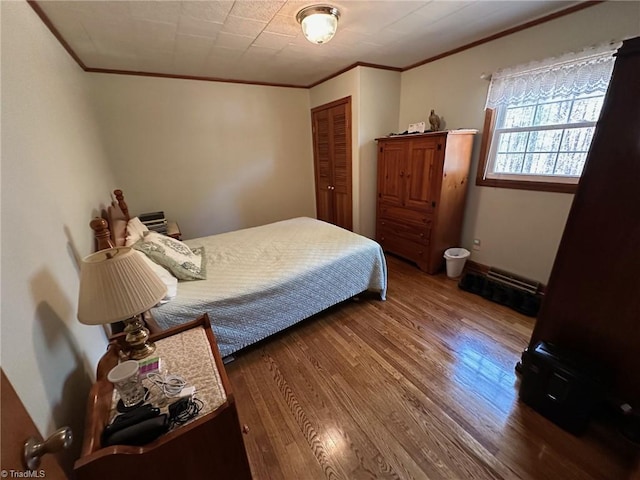 bedroom featuring baseboards, wood finished floors, a closet, and ornamental molding