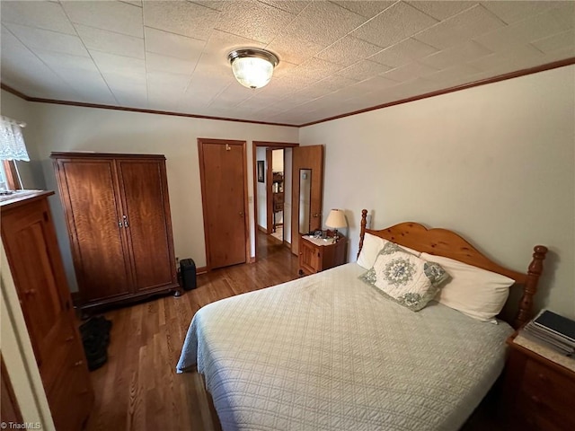 bedroom featuring crown molding and wood finished floors