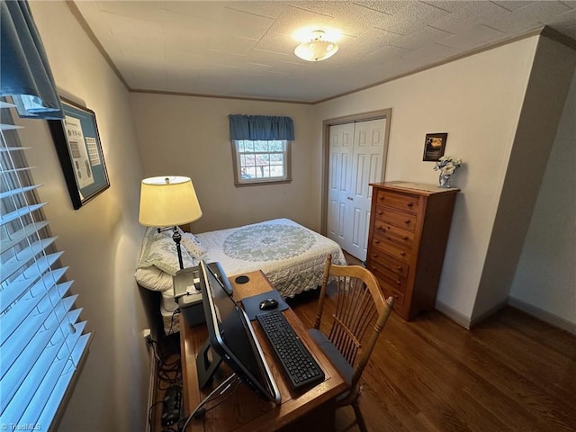 bedroom with a closet, baseboards, wood finished floors, and ornamental molding