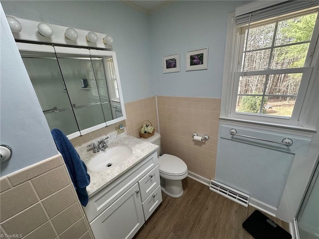 full bath with visible vents, toilet, wood finished floors, tile walls, and wainscoting