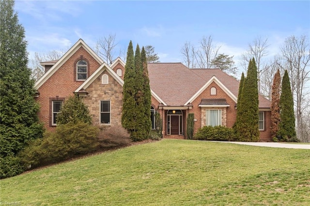 view of front of property featuring a front yard, brick siding, and stone siding