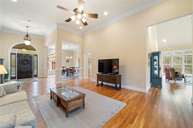 living room featuring ceiling fan with notable chandelier, baseboards, light wood-style floors, and ornamental molding