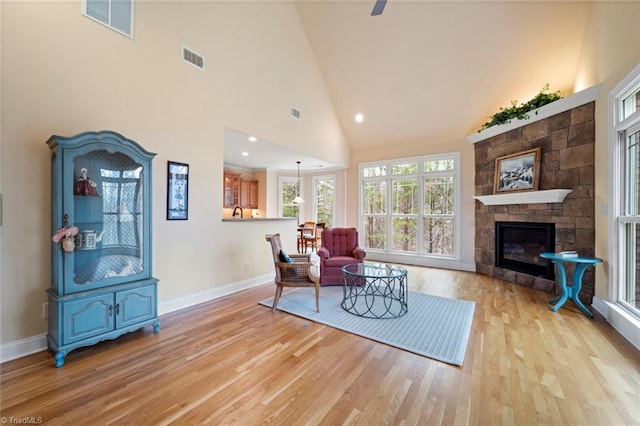 living area featuring light wood-style floors, a fireplace, visible vents, and baseboards