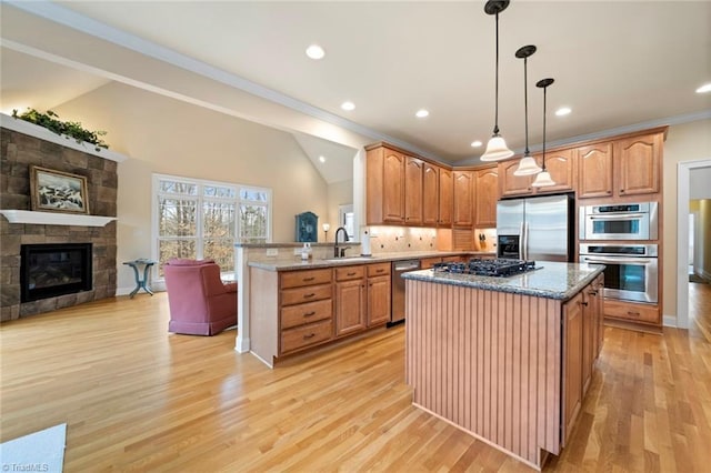 kitchen featuring a sink, light wood-style floors, appliances with stainless steel finishes, a peninsula, and lofted ceiling