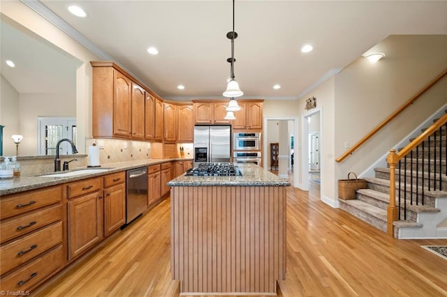 kitchen featuring a sink, light stone counters, appliances with stainless steel finishes, and a center island