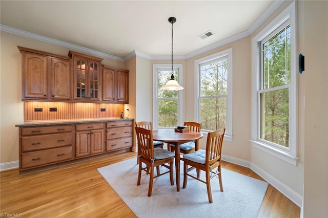 dining space with light wood-type flooring, baseboards, visible vents, and ornamental molding