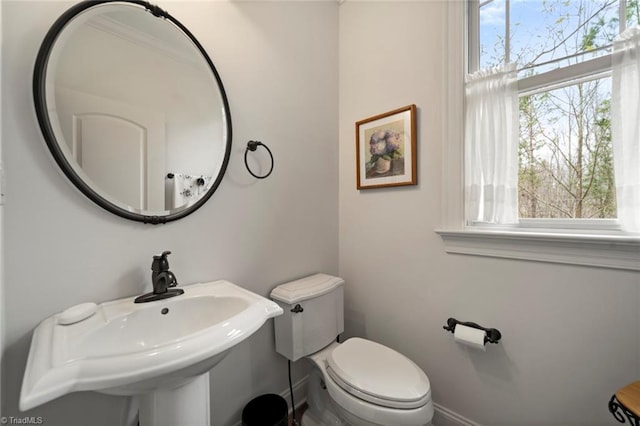 bathroom featuring toilet, baseboards, and a sink