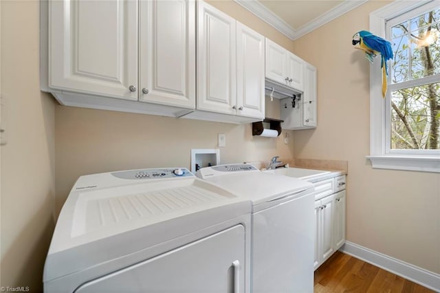 clothes washing area featuring crown molding, baseboards, washer and clothes dryer, cabinet space, and a sink