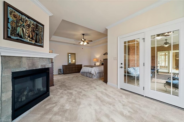 bedroom featuring carpet floors, ornamental molding, a glass covered fireplace, a raised ceiling, and access to outside