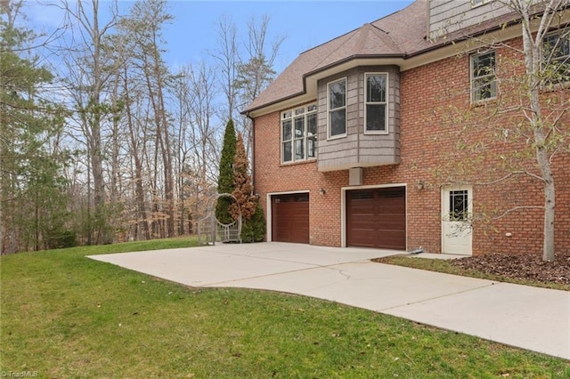 view of home's exterior featuring brick siding, a garage, concrete driveway, and a yard