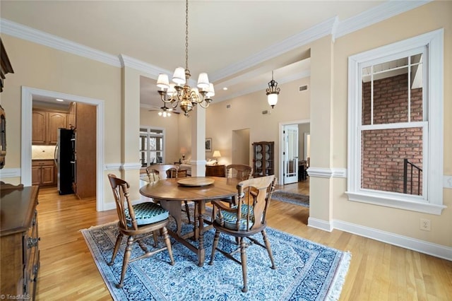 dining room with an inviting chandelier, baseboards, crown molding, and light wood-style floors