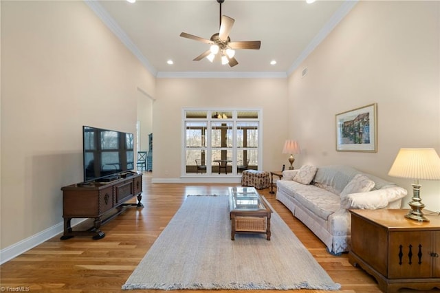 living area featuring light wood finished floors, a high ceiling, crown molding, and baseboards