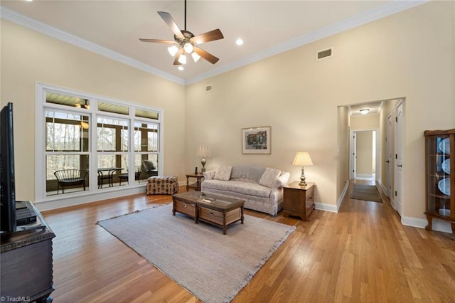 living area featuring crown molding, light wood-style flooring, baseboards, and visible vents