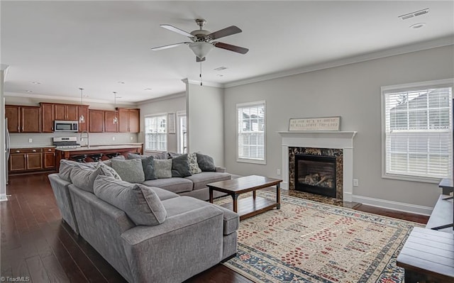 living room with ceiling fan, sink, ornamental molding, a high end fireplace, and dark hardwood / wood-style floors