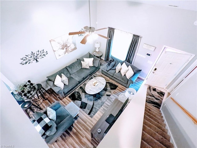 living room with ceiling fan, high vaulted ceiling, and wood-type flooring