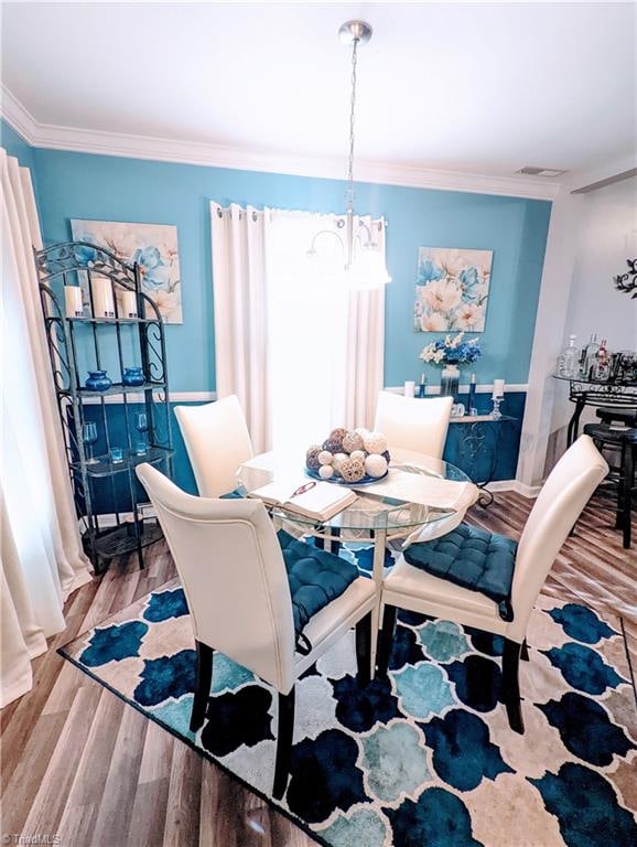 dining room featuring light hardwood / wood-style flooring, ornamental molding, and a notable chandelier