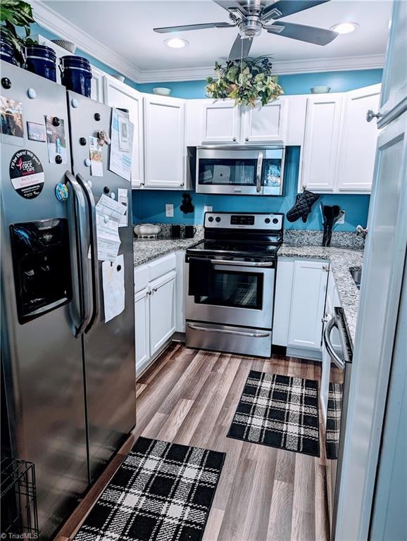 kitchen featuring ornamental molding, white cabinets, stainless steel appliances, and hardwood / wood-style floors