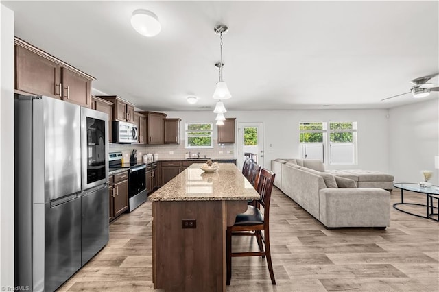 574 Freeport Ct, Winston-Salem, NC 27127 - kitchen with stainless steel appliances, open floor plan, dark brown cabinets, and plenty of natural light