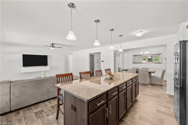 574 Freeport Ct, Winston-Salem, NC 27127 - kitchen with freestanding refrigerator, a kitchen bar, light wood-style flooring, open floor plan, and dark brown cabinetry