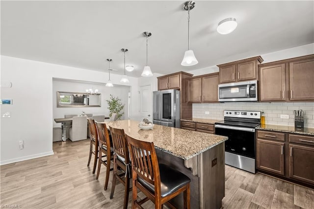 574 Freeport Ct, Winston-Salem, NC 27127 - kitchen with stainless steel appliances, a breakfast bar area, light wood-type flooring, and decorative backsplash