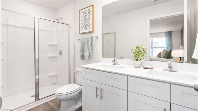 bathroom with toilet, vanity, an enclosed shower, and hardwood / wood-style flooring