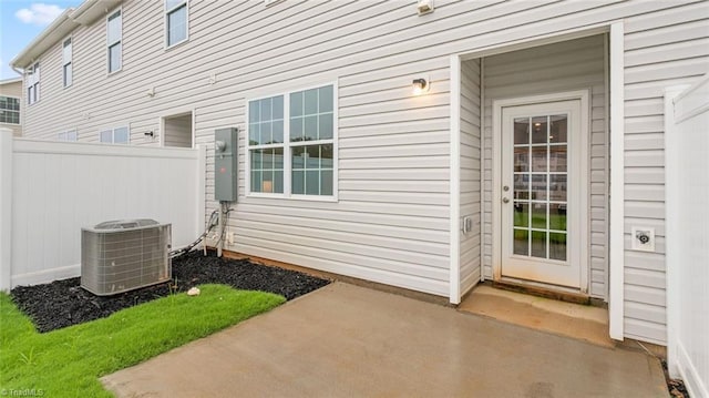 view of exterior entry with central air condition unit and a patio