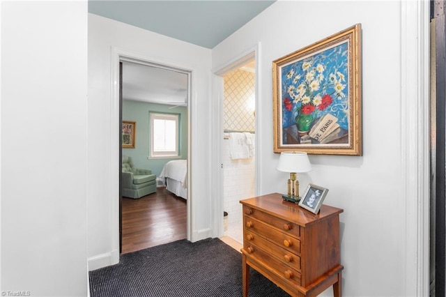 hall with baseboards and dark colored carpet