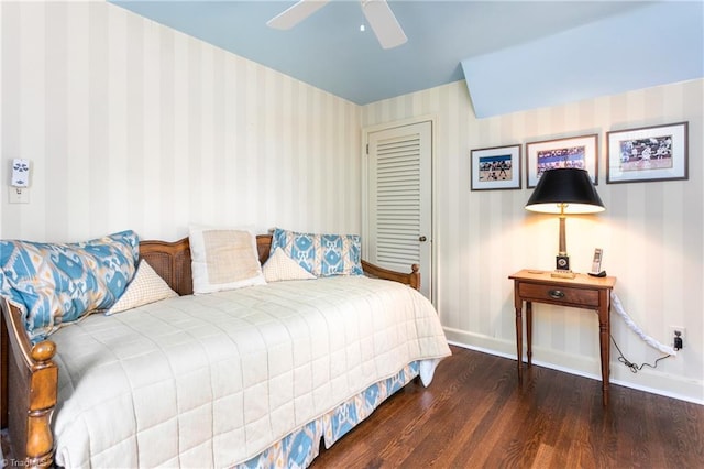 bedroom with a closet, wood finished floors, baseboards, ceiling fan, and wallpapered walls