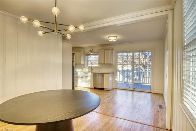 unfurnished dining area with light wood-type flooring, ornamental molding, sink, and a chandelier