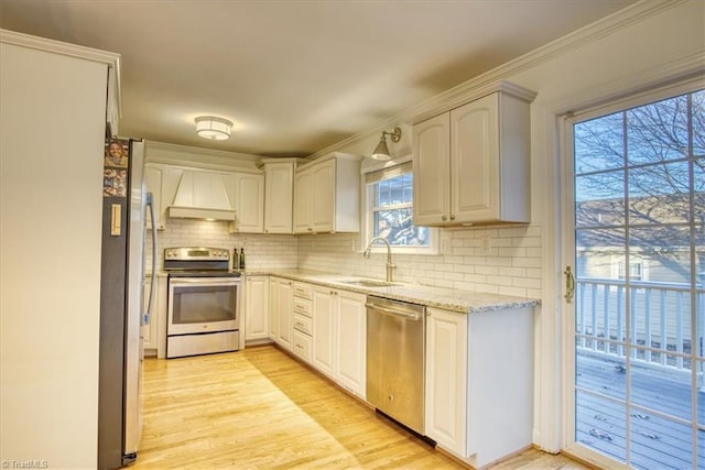 kitchen with white cabinetry, sink, custom range hood, and appliances with stainless steel finishes