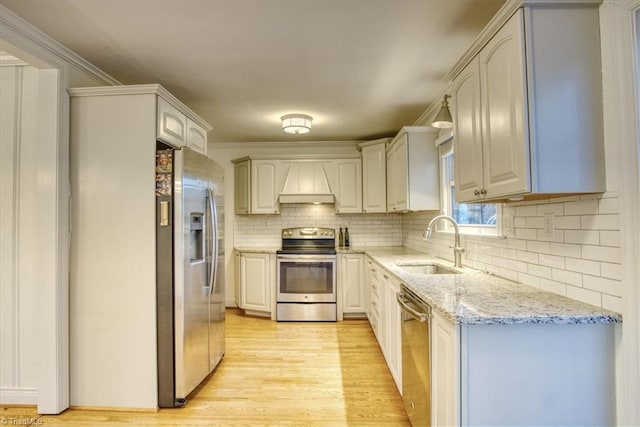 kitchen featuring sink, premium range hood, crown molding, appliances with stainless steel finishes, and light wood-type flooring