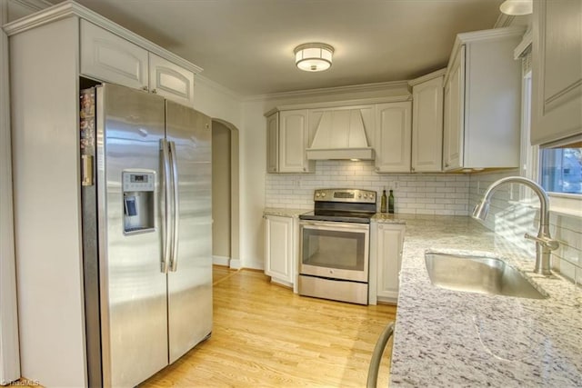 kitchen featuring white cabinets, custom range hood, stainless steel appliances, and sink