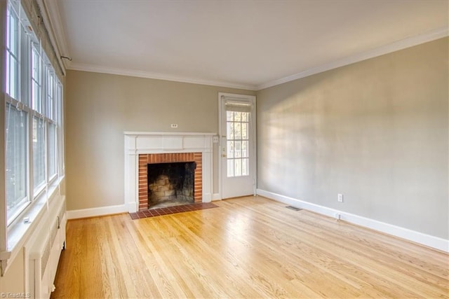 unfurnished living room featuring crown molding, light wood-type flooring, and a brick fireplace