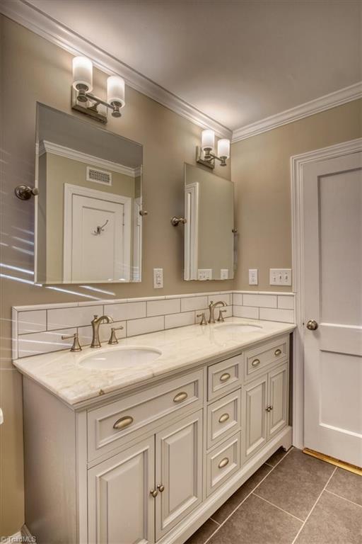 bathroom featuring tasteful backsplash, crown molding, tile patterned flooring, and vanity