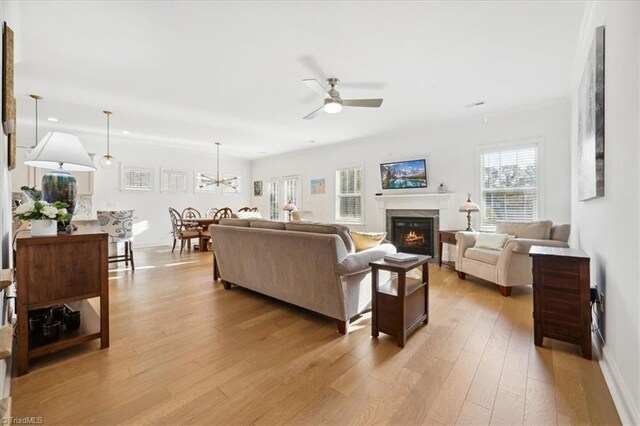 755 Gibb St, Winston-Salem, NC 27106 - living area featuring a glass covered fireplace, ceiling fan, light wood finished floors, a chandelier, and baseboards