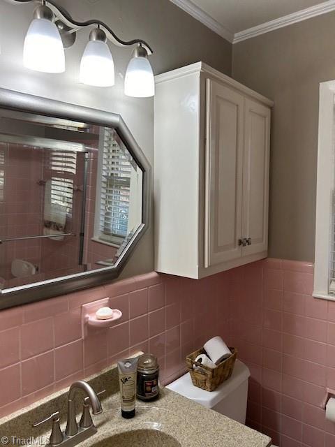 bathroom featuring tile walls, sink, ornamental molding, and toilet