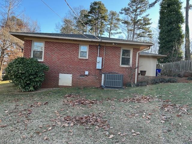 view of side of home with central AC and a yard