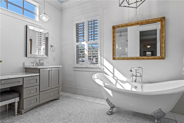 full bath featuring a wealth of natural light, a freestanding bath, vanity, and baseboards