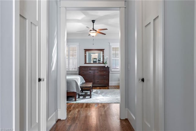 hallway featuring baseboards, ornamental molding, and dark wood-type flooring