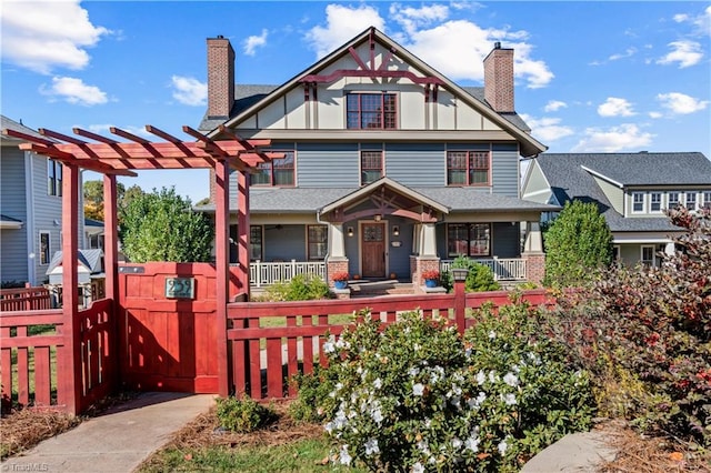 view of front of house with a porch, a chimney, and a fenced front yard