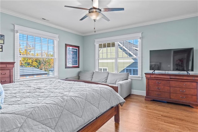 bedroom featuring baseboards, visible vents, crown molding, and light wood finished floors