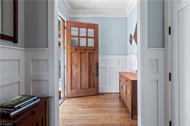 foyer with a wainscoted wall, a decorative wall, light wood-type flooring, and crown molding