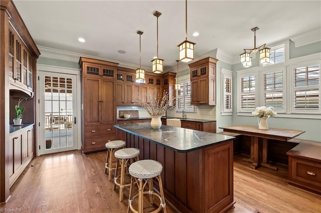 239 Glade View Ct, Winston-Salem, NC 27101 - kitchen featuring a kitchen island, crown molding, wood finished floors, a breakfast bar, and brown cabinetry