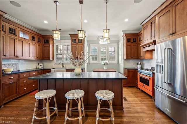239 Glade View Ct, Winston-Salem, NC 27101 - kitchen with high end appliances, dark countertops, crown molding, dark wood-style flooring, and a kitchen island