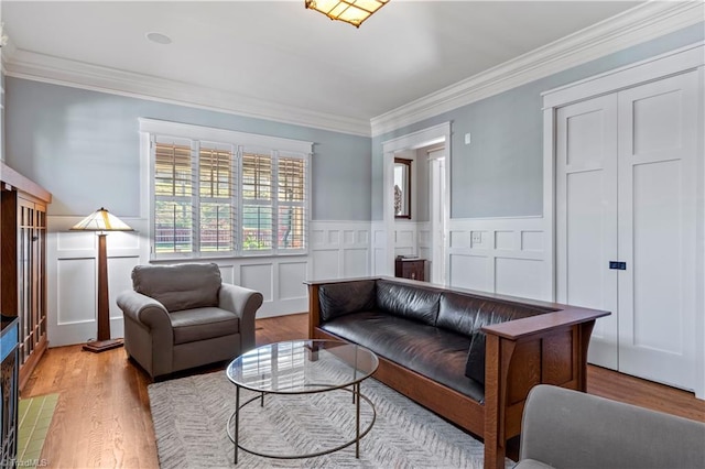 living area featuring a wainscoted wall, light wood finished floors, and crown molding